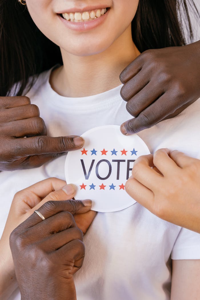 A diverse group advocating democracy with a vote sticker.